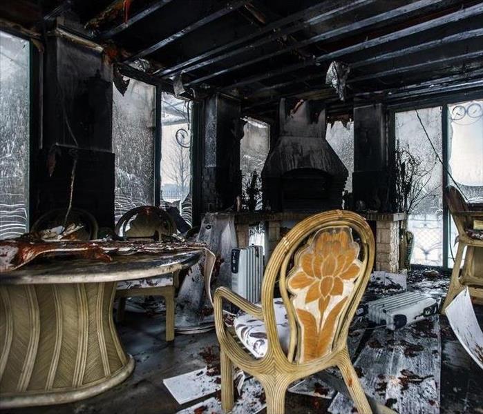 Living room suffered fire loss, chairs and wall covered with soot.