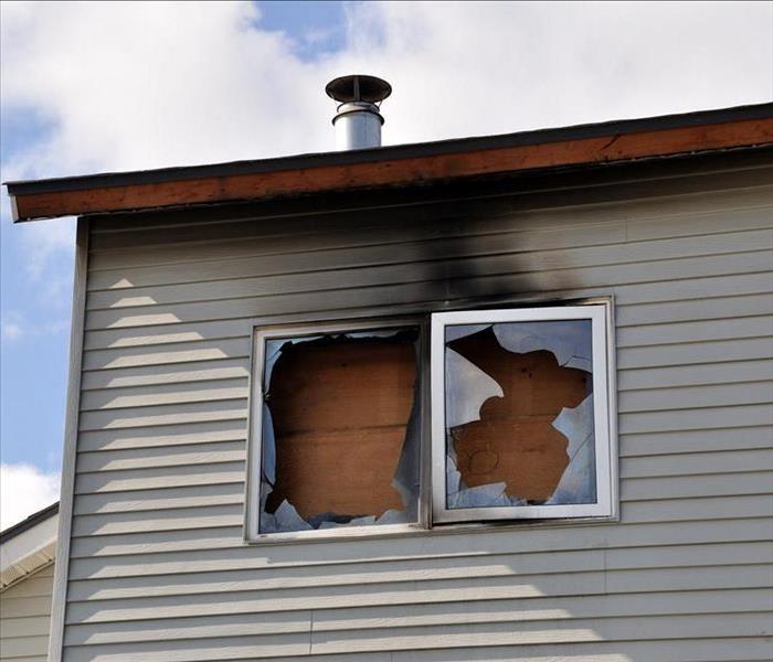Broken window, window frame with smoke., window boarded up. Concept of fire damage in a home. Board up services.